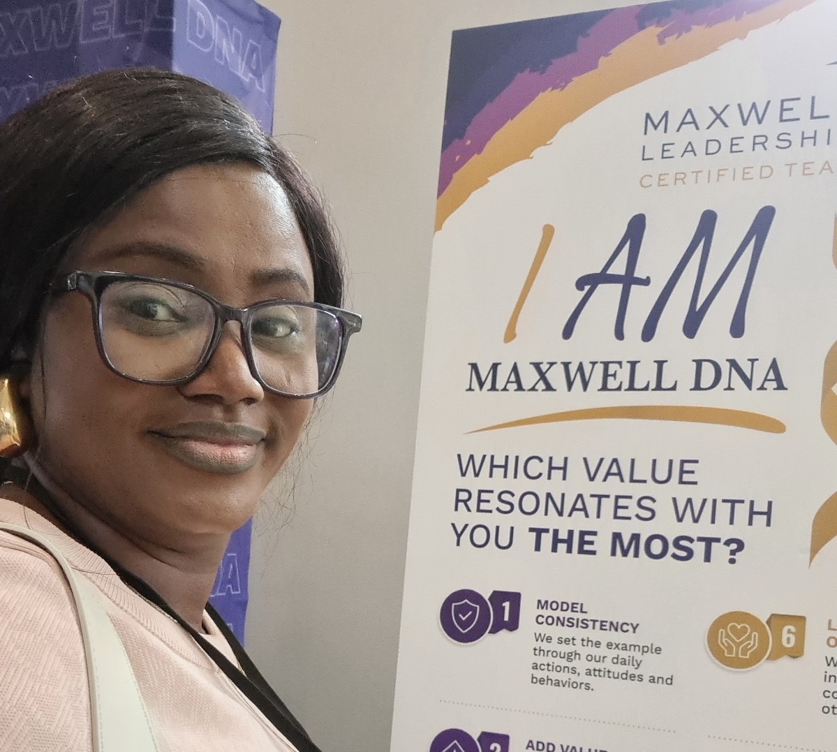 Kemi Areola beside a Maxwell Leadership 'I Am Maxwell DNA' values board